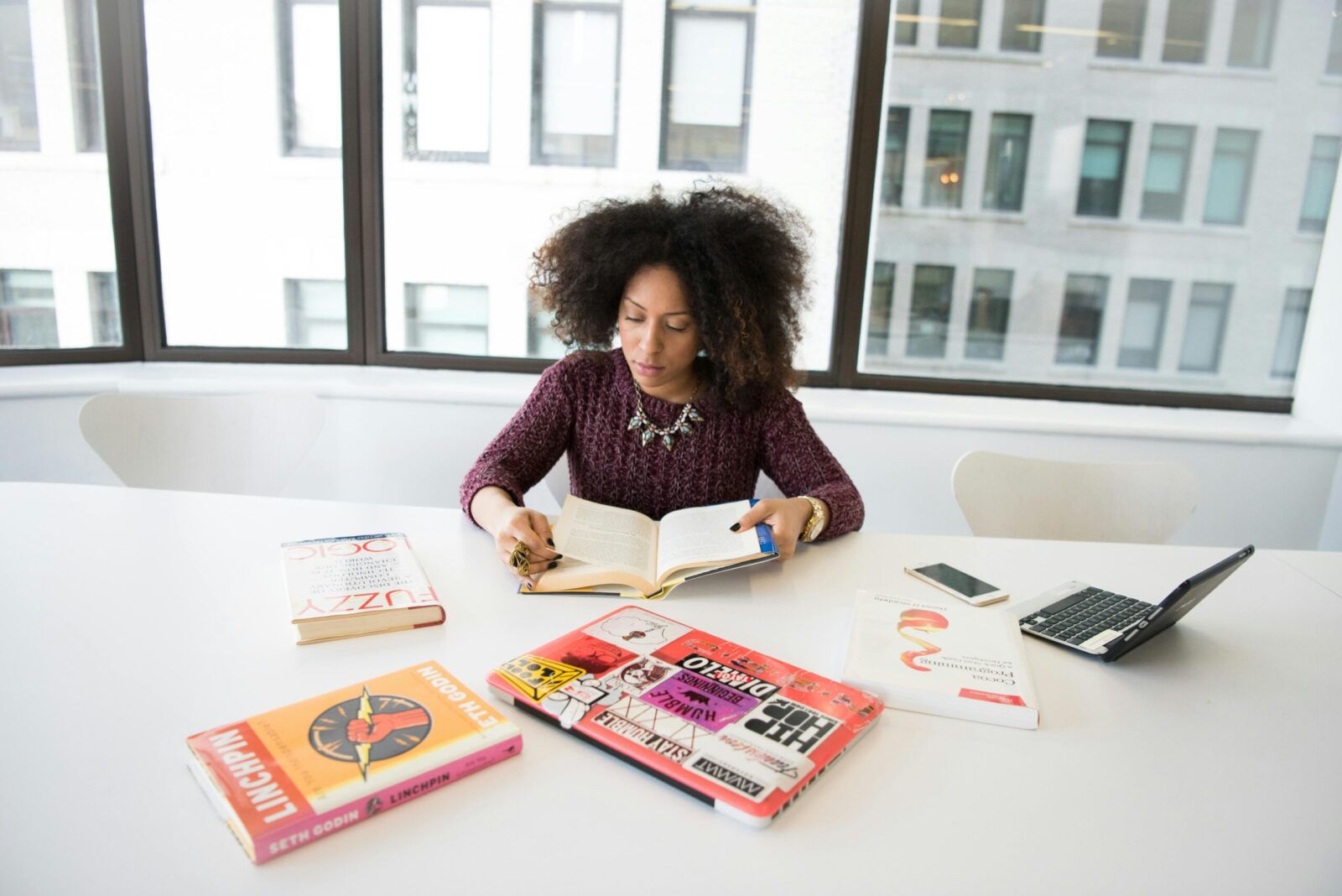 A focused woman working in an office environment, studying and reading research material.